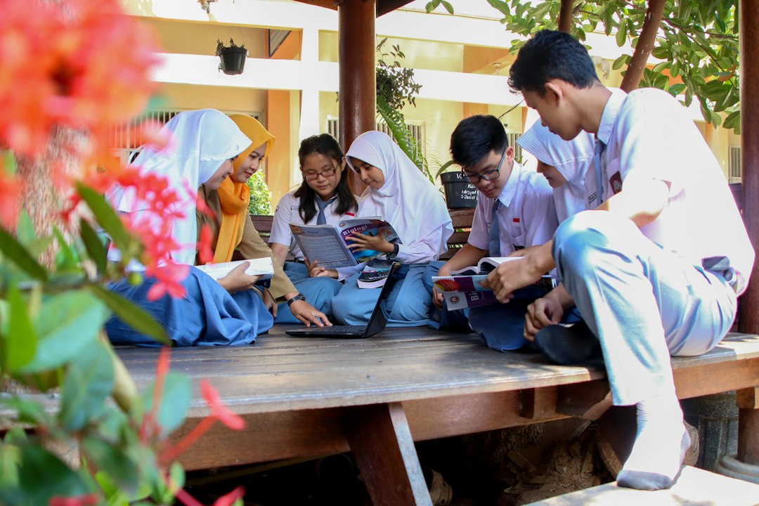 Teacher supporting secondary-school students as they work together in a classroom, representing critical evaluation of AI-assisted learning.