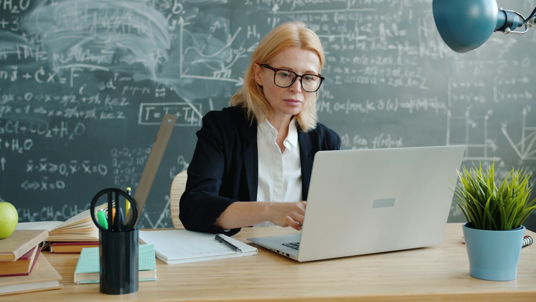 University instructor reviewing student work on a laptop in a classroom